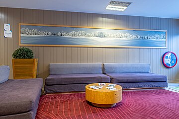 A painting of a snowy landscape hangs above a couch
