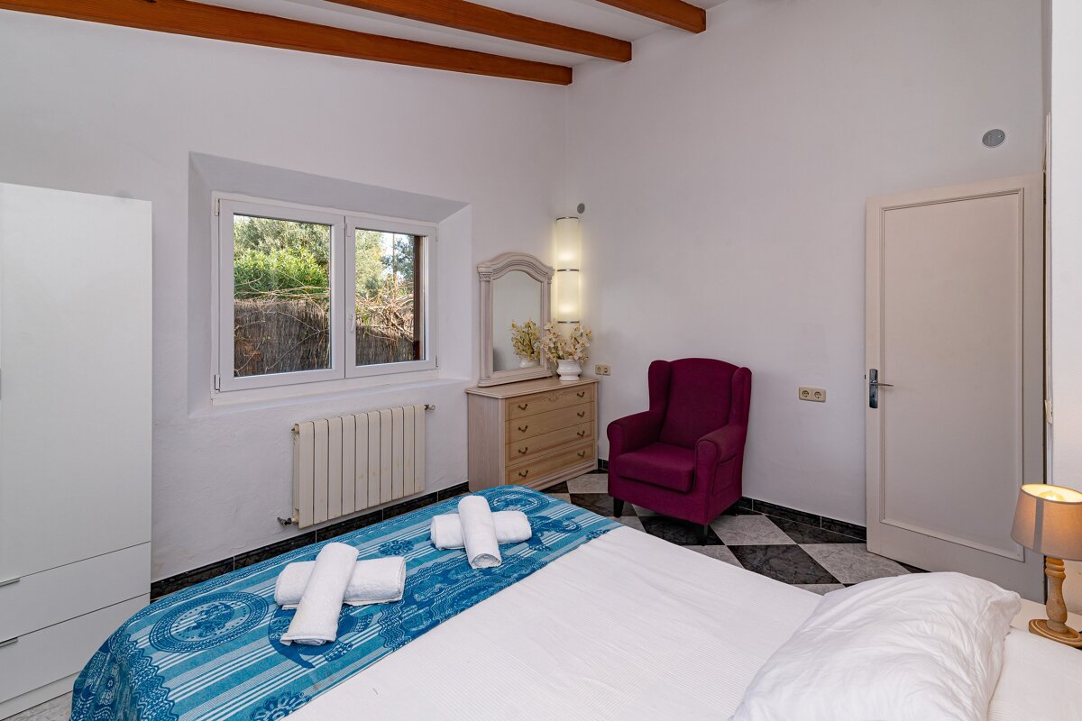 A bedroom with a bed a dresser and a chair