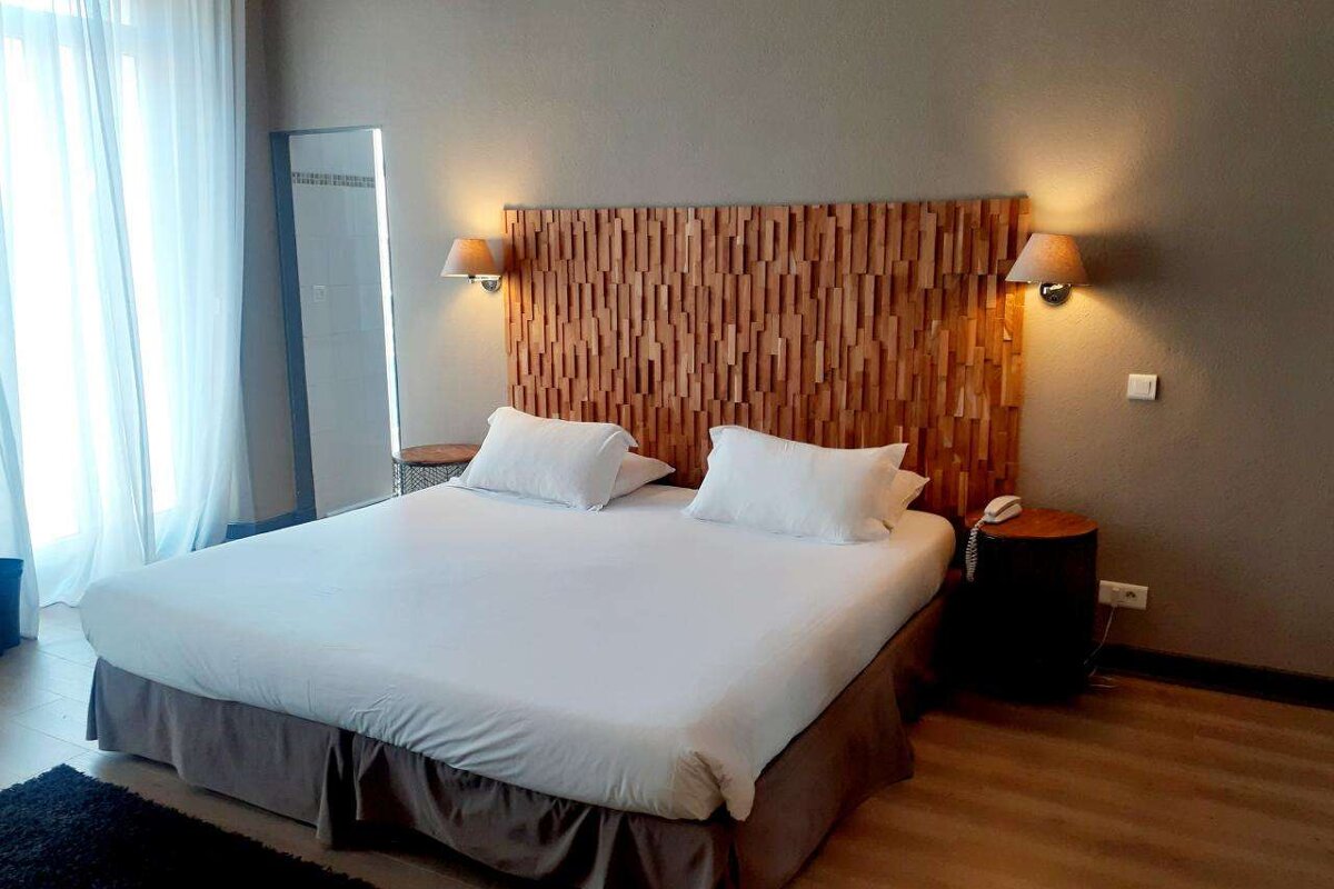 A hotel room with a large bed and a wooden headboard