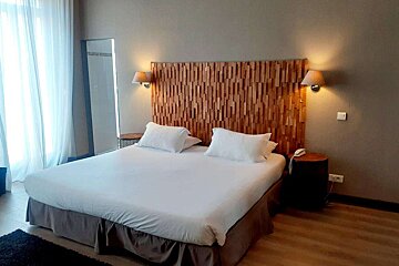 A hotel room with a large bed and a wooden headboard