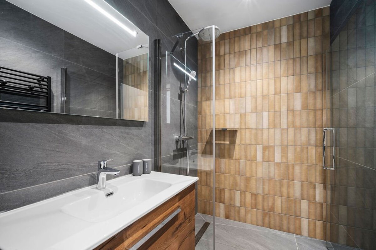 A bathroom with a walk in shower and a sink