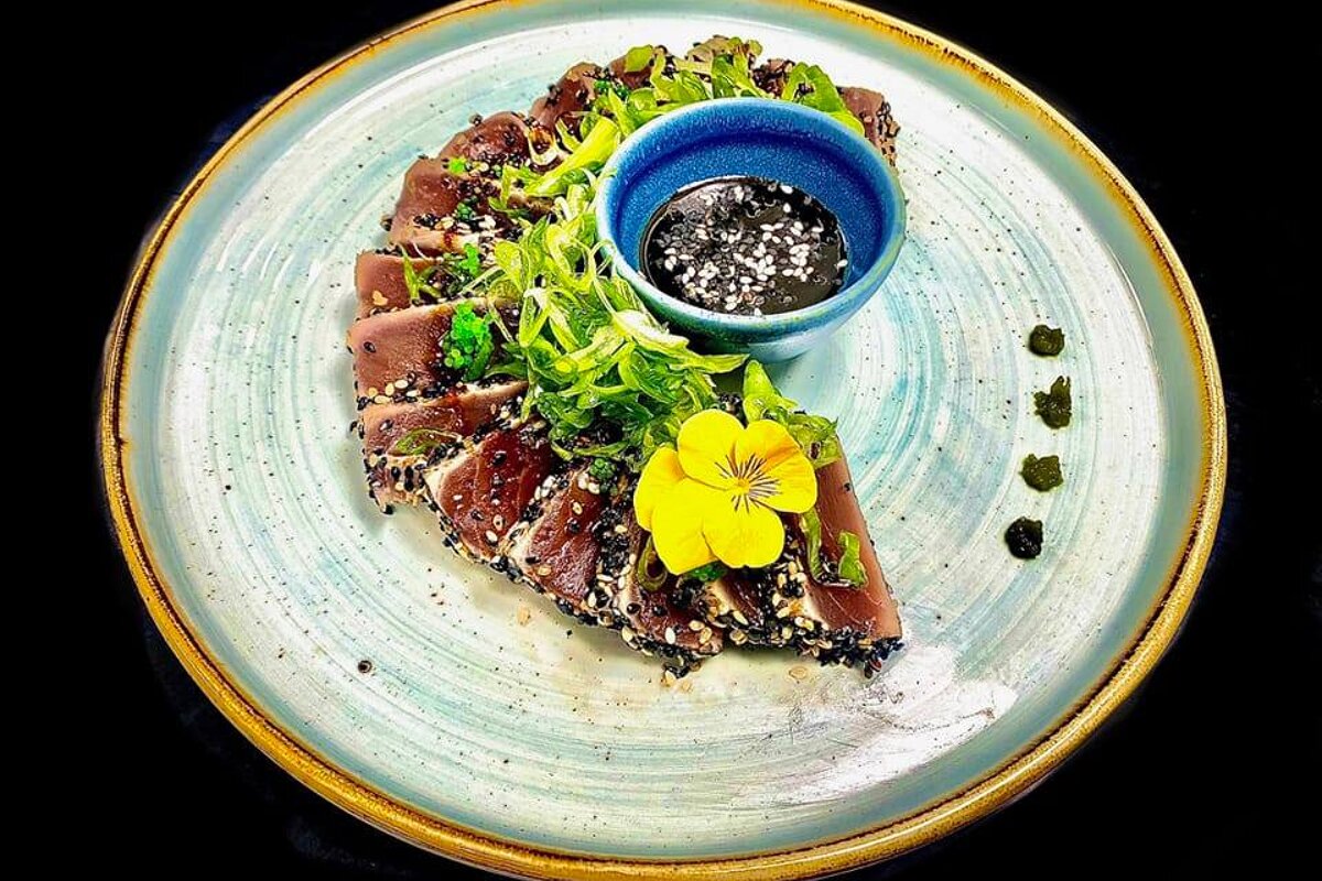 A plate of food with a blue bowl of dipping sauce