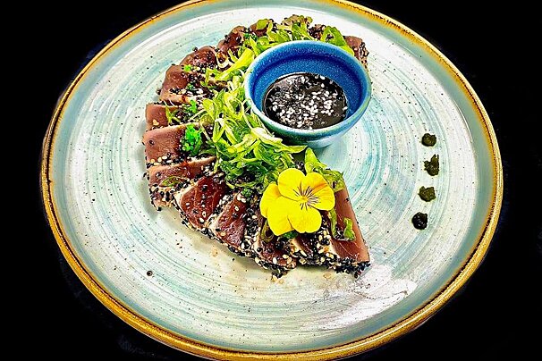 A plate of food with a blue bowl of dipping sauce