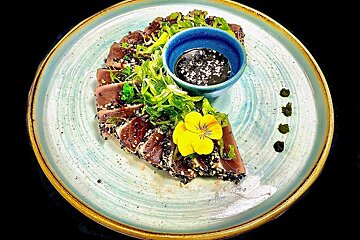 A plate of food with a blue bowl of dipping sauce