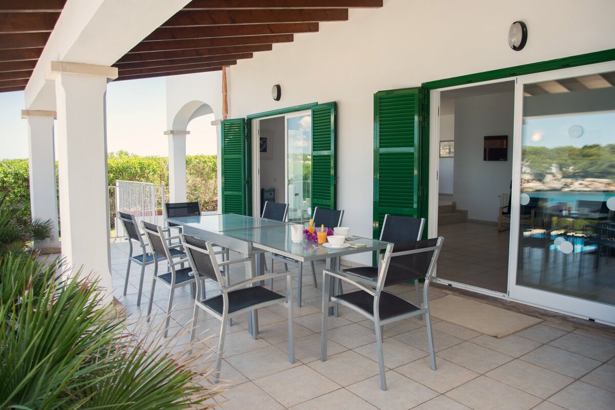 A patio with a table and chairs and green shutters