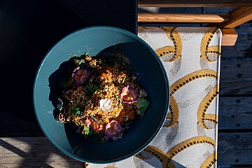A blue bowl of food sits on a yellow and white table cloth