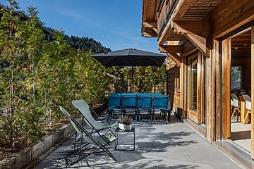 A patio with chairs and an umbrella in front of a wooden building