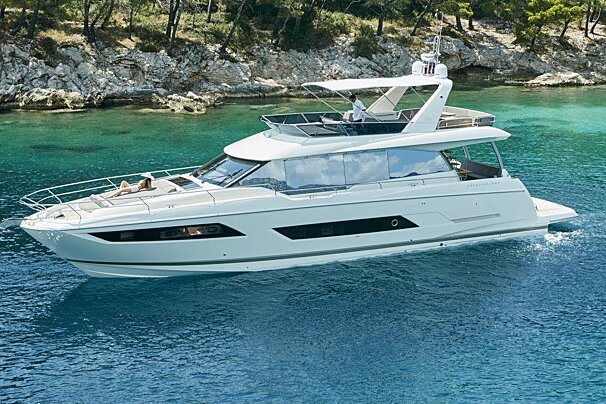 A white yacht is floating in the water near a rocky shoreline