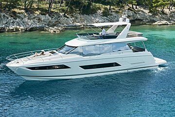 A white yacht is floating in the water near a rocky shoreline