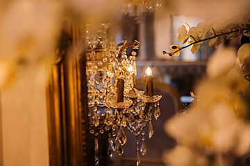 A chandelier is lit up in front of a mirror