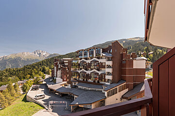 A view of a large building with mountains in the background