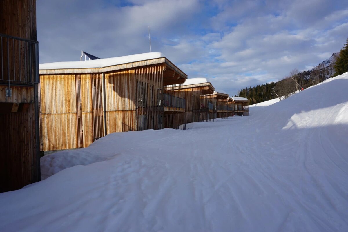 A snowy path leading to a row of wooden houses
