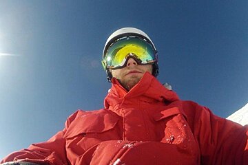 A man in a red jacket is wearing a helmet and goggles