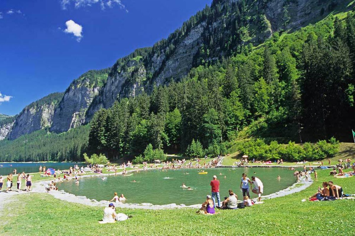 A group of people are swimming in a lake surrounded by mountains