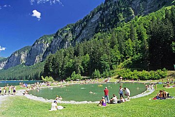 A group of people are swimming in a lake surrounded by mountains