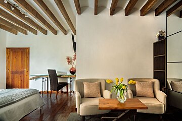 A room with two chairs and a table with a vase of flowers on it