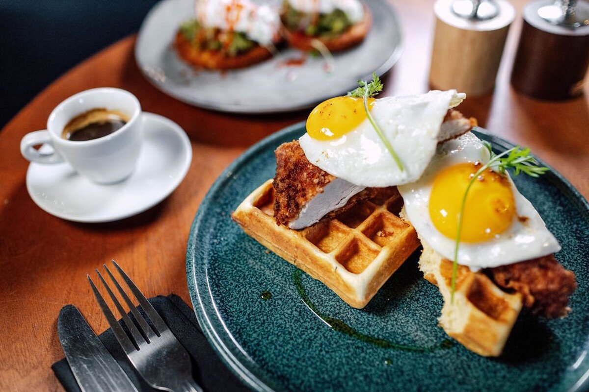 A waffle with fried eggs and chicken on it