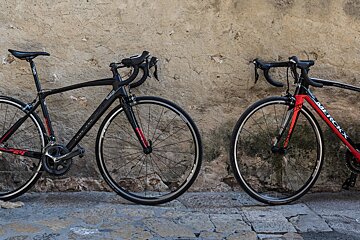 Two bicycles one black and one red are parked next to each other