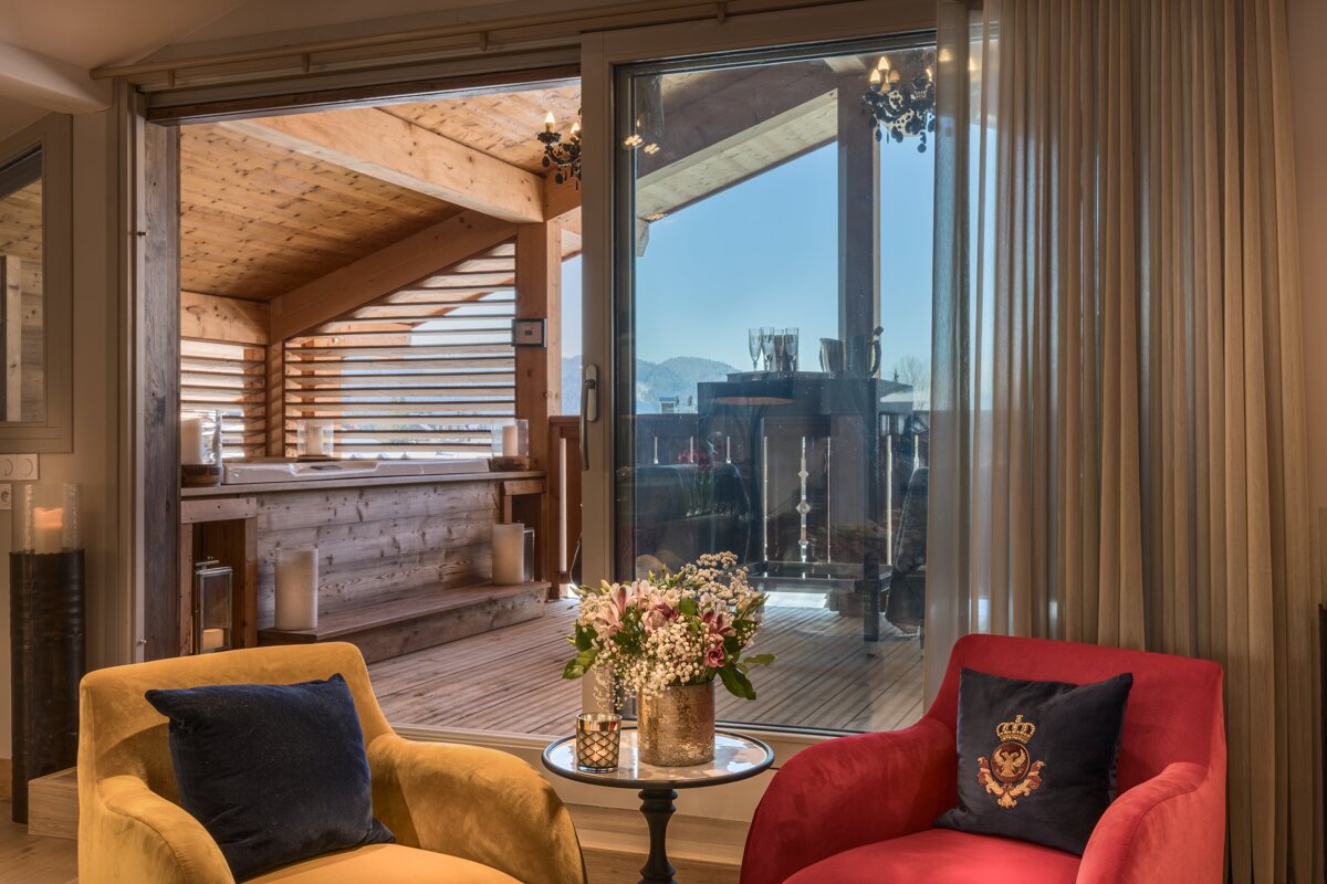 A room with two chairs and a table with a vase of flowers on it