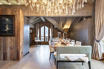 A dining room with a long table and chairs and a chandelier