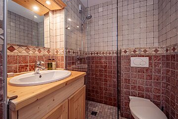 A bathroom with red and white tiles and a toilet