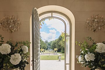 A doorway with flowers in front of it and a view of a garden