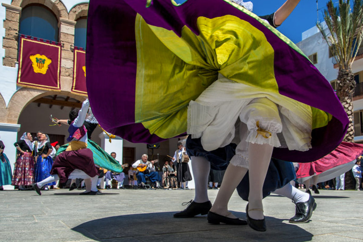 A woman in a purple and yellow dress is dancing