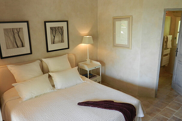 A bedroom with a bed and two framed pictures on the wall