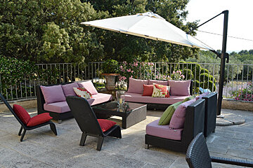 A patio area with a white umbrella and purple furniture