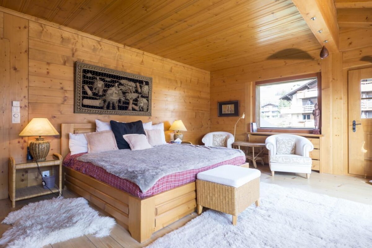A bedroom with a large bed and two chairs