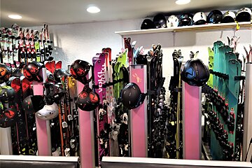 A busy ski shop showcasing numerous colorful skis and helmets on racks and shelves, ready for winter sports.