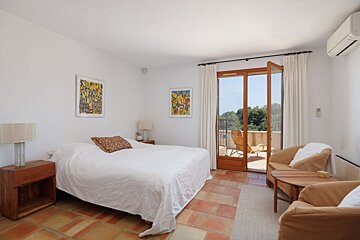 A bedroom with a large bed and a chair