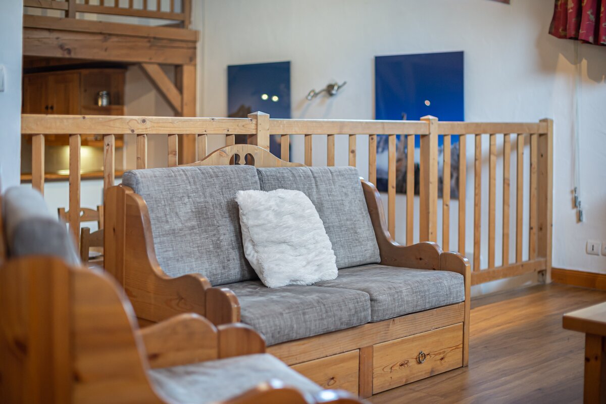 A wooden couch with a white pillow on it