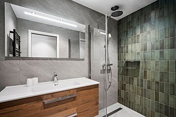 A bathroom with green tiles and a walk in shower