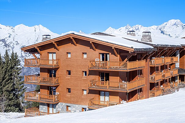 A large wooden building with balconies and mountains in the background