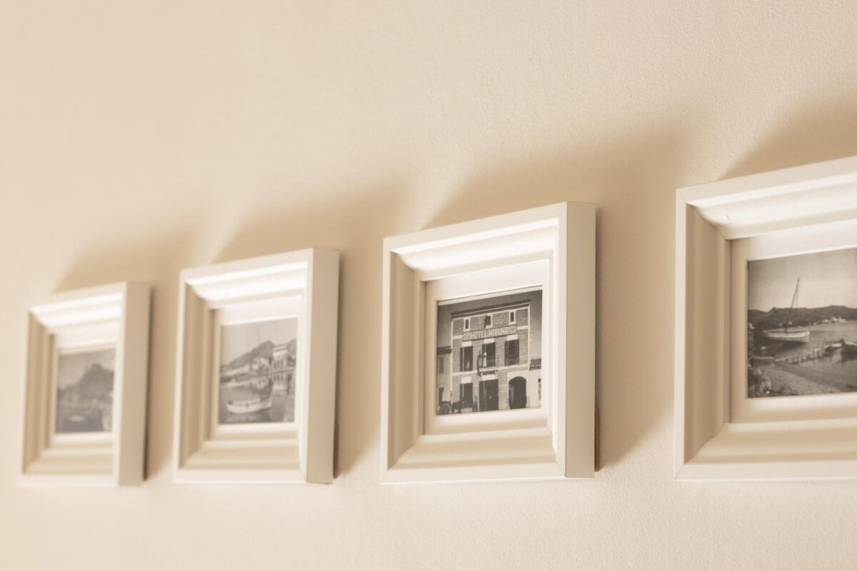 Four small white-framed vintage black-and-white photos hanging in a neat row on a warm beige wall.