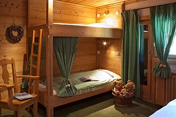 A bunk bed with green curtains and a basket of teddy bears