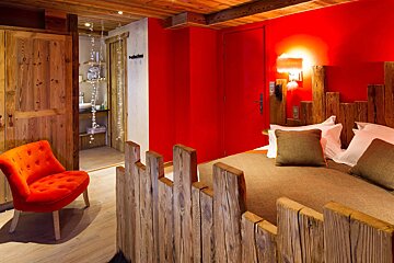 A bedroom with red walls and wooden furniture