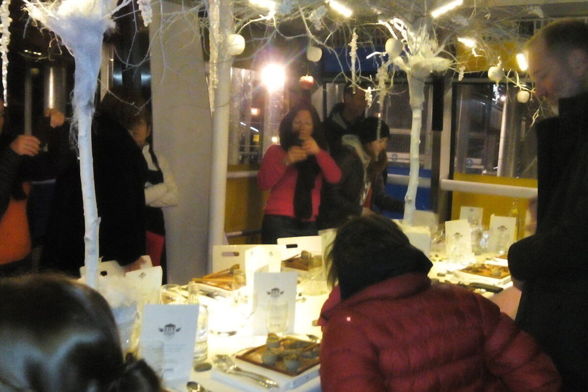 People starting to sit around a white table with jackets on and taking photos inside of the cabin