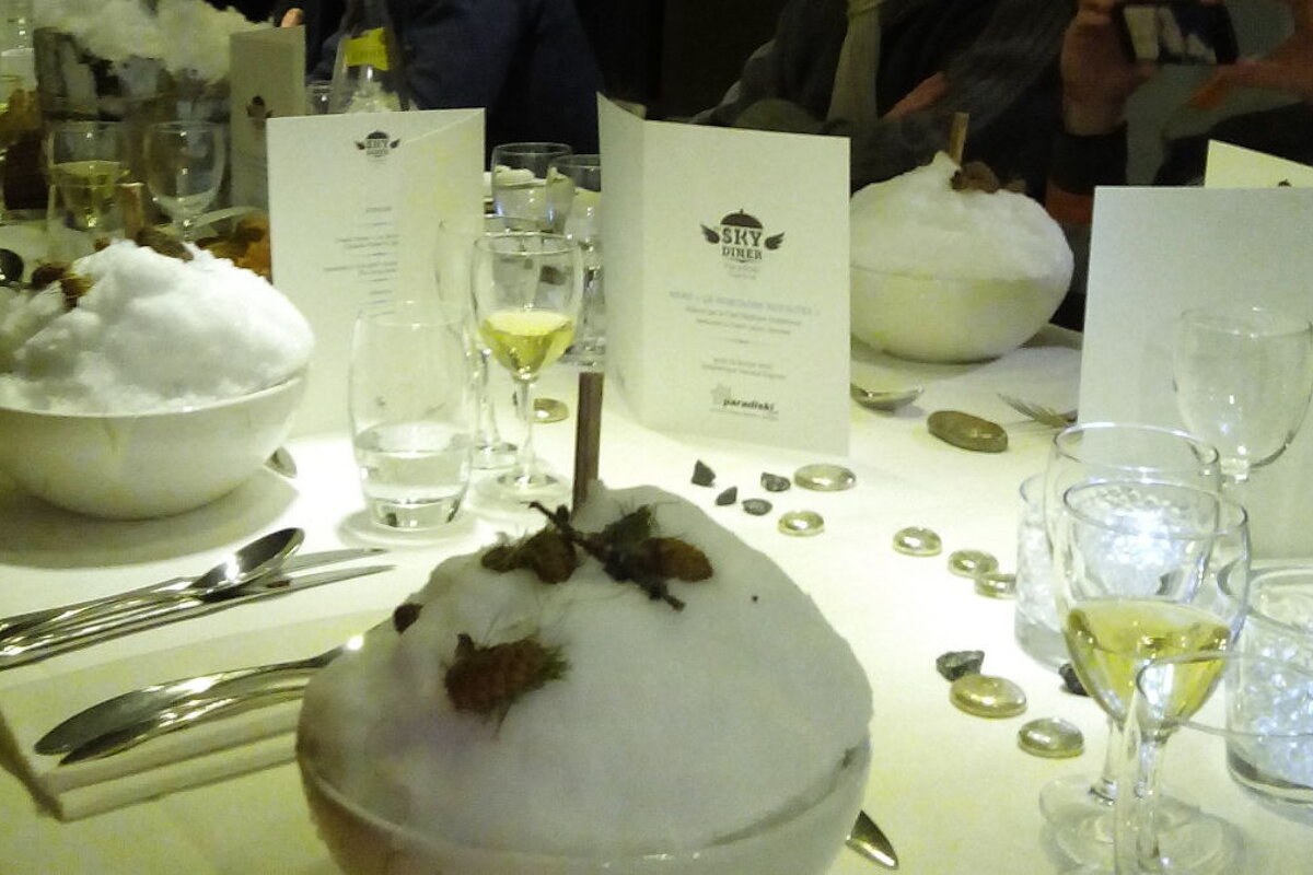 Large bowls of snow with straws sticking out of them on a table with cutlery and glasses and menus