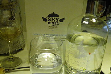 Glass of wine, glass of water, bottler of water and a skydiner menu