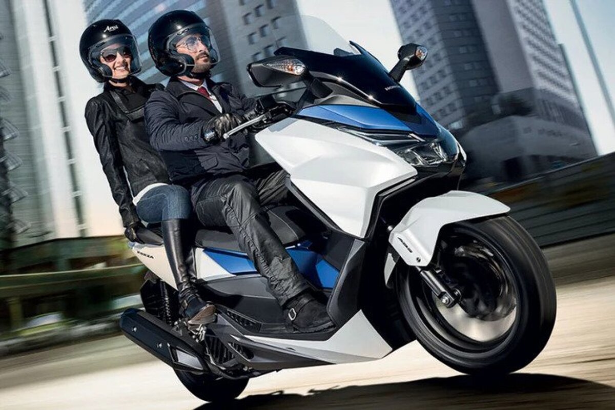 A man and a woman are riding a honda scooter