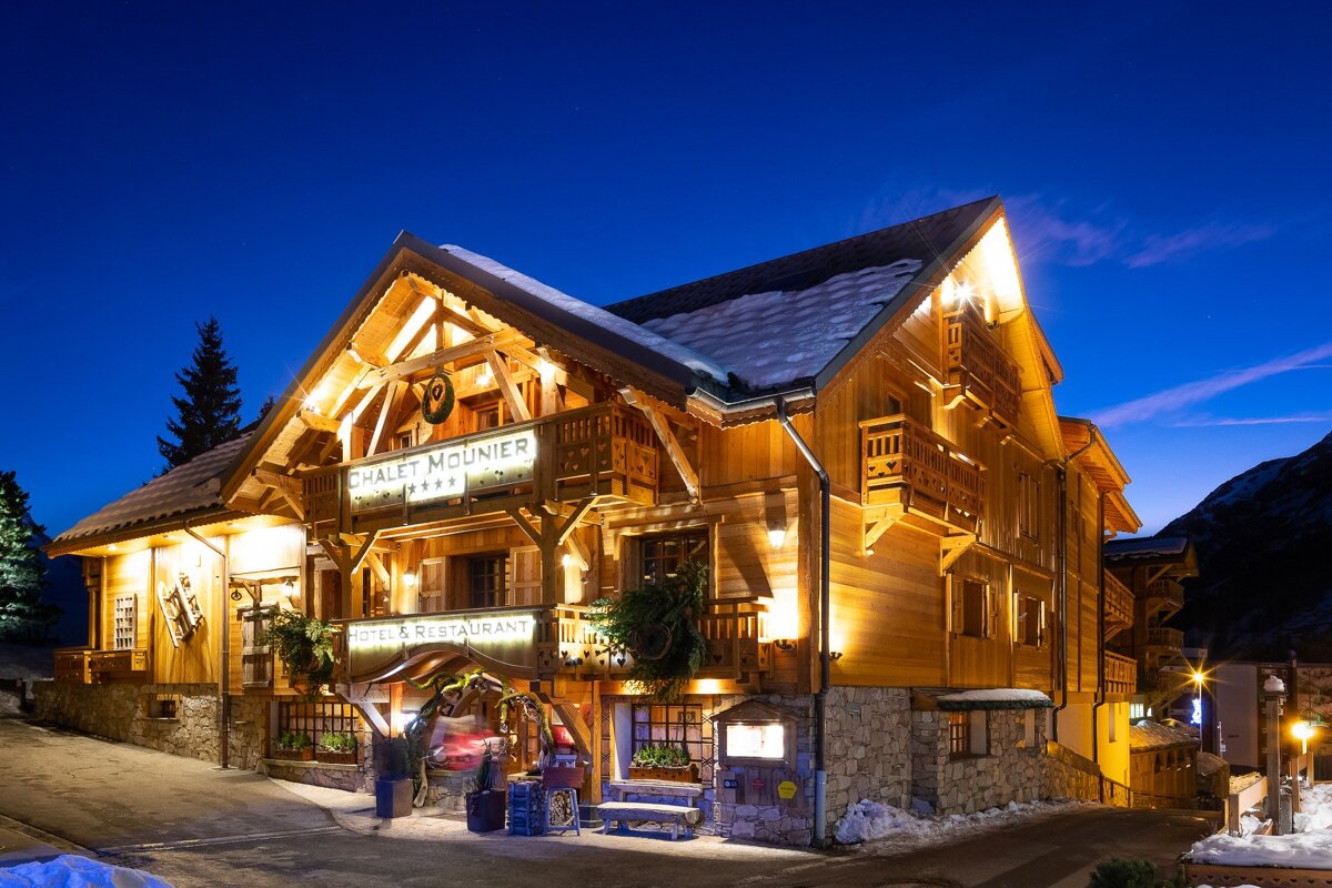 A chalet mountier hotel is lit up at night