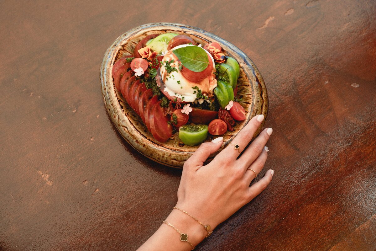 A woman 's hand reaches for a plate of food on a table
