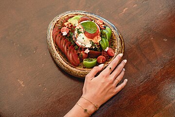 A woman 's hand reaches for a plate of food on a table
