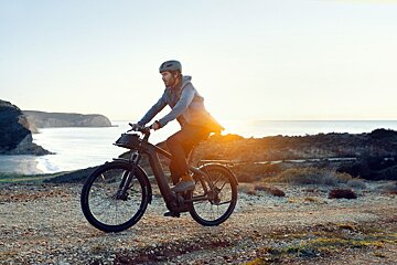 A man wearing a helmet is riding an electric bike