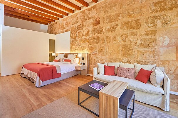 A bedroom with a bed and a couch with red pillows