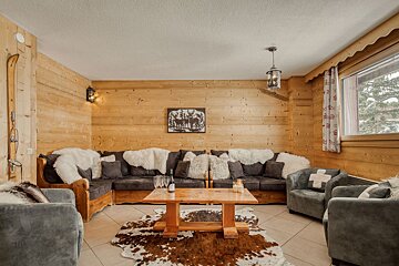 A living room with a couch and chairs and a table with a bottle of wine on it