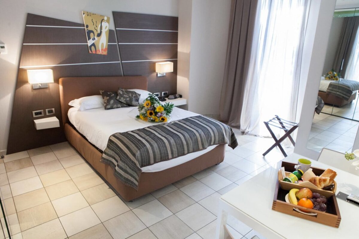 A hotel room with a bed and a tray of food on the table