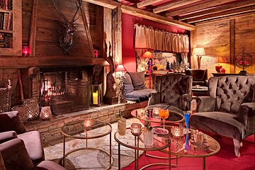 A living room with a fireplace and tables with candles on them